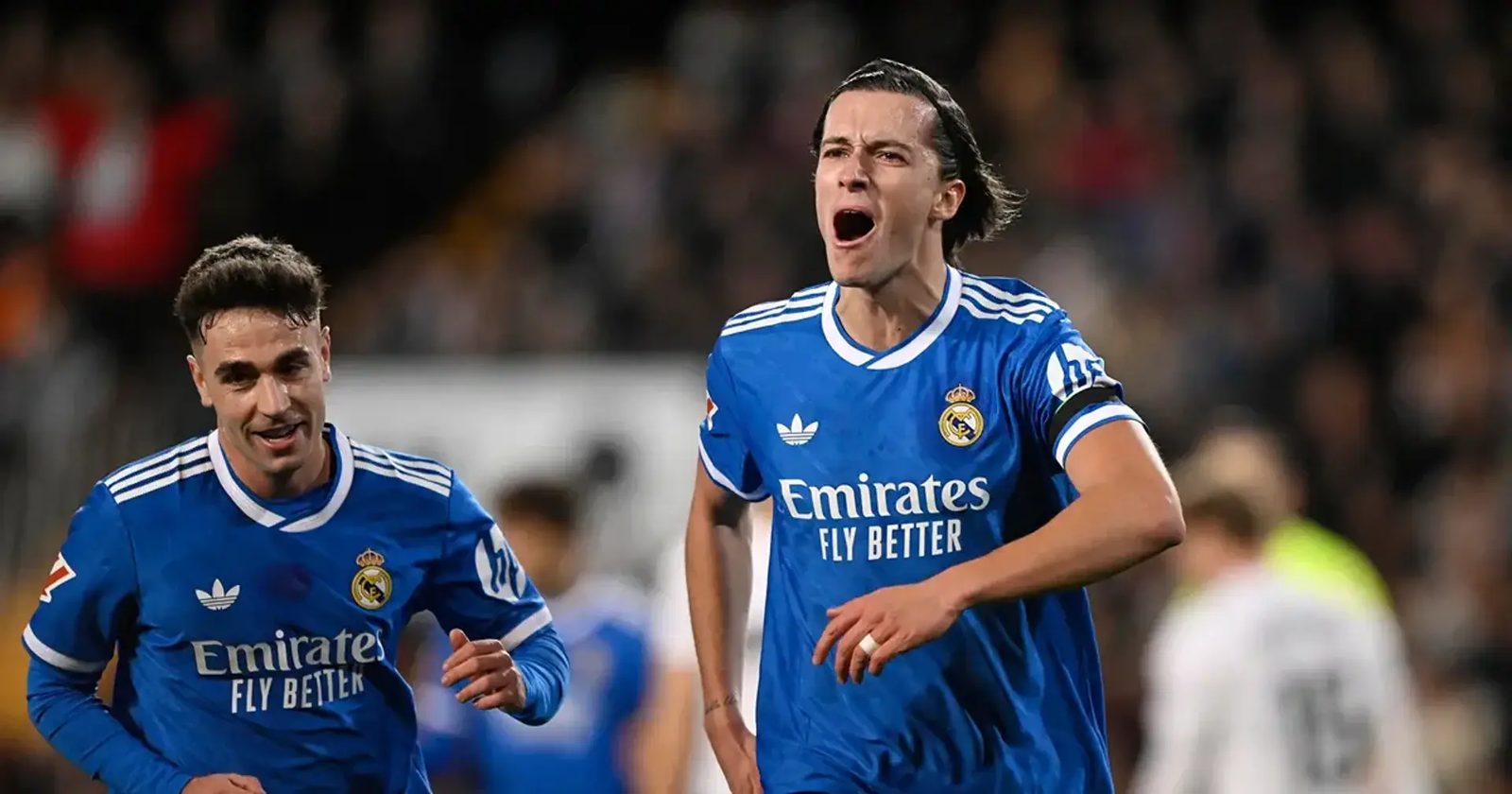 Persona corriendo y celebrando con camiseta azul del Real Madrid tras una victoria contra el Valencia, en un ambiente lleno de emoción y energía futbolera.