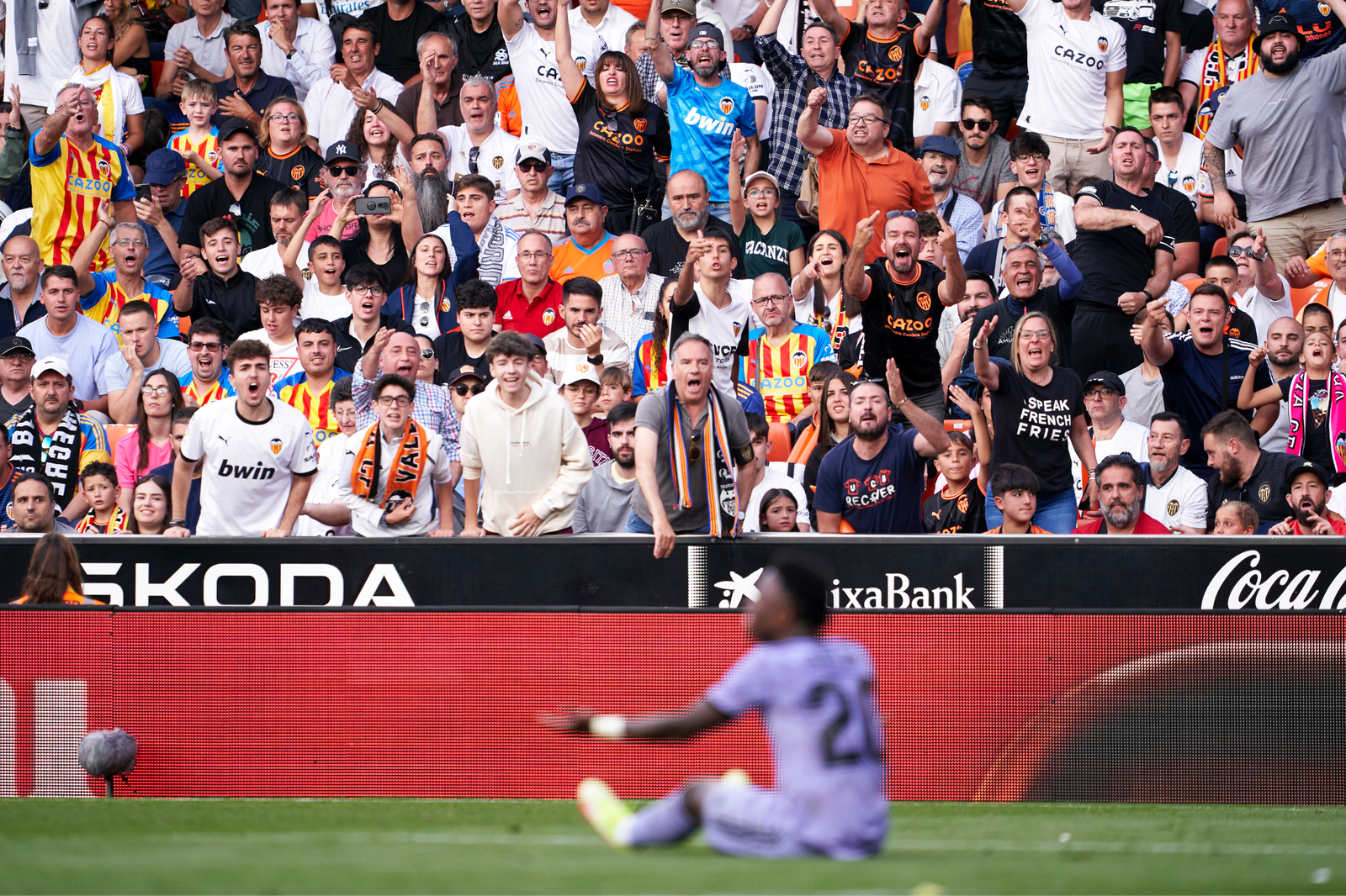 Vinícius Júnior desenfocado mientras aficionados del Valencia reaccionan desde la grada durante el partido marcado por incidentes racistas.